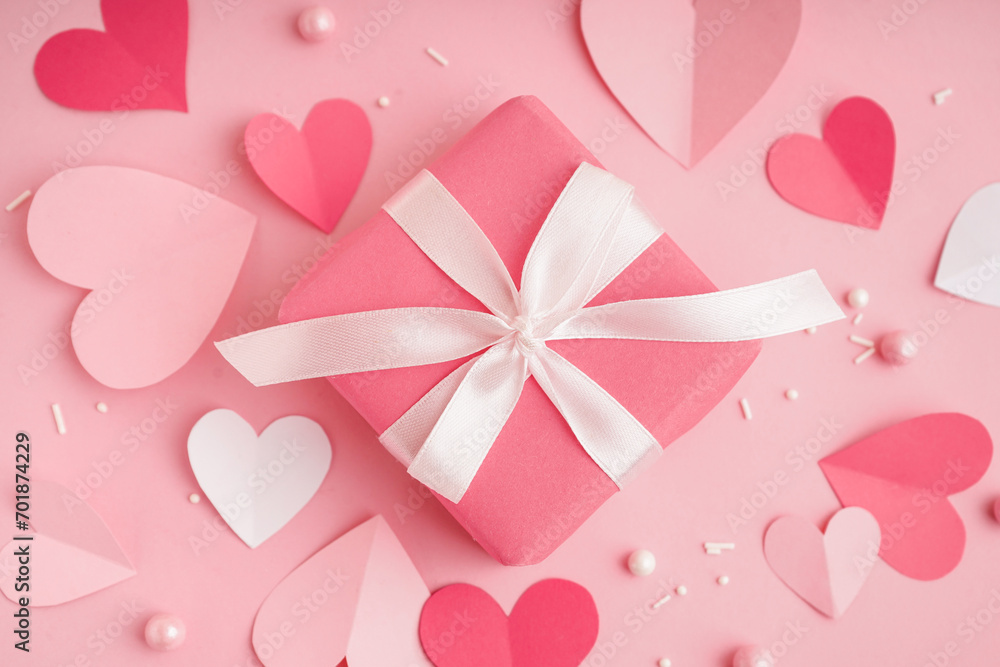 Gift box with paper hearts and decor on pink background. Valentine's Day celebration