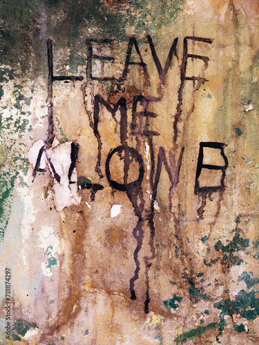 Leave Me Alone message on abandoned wall
