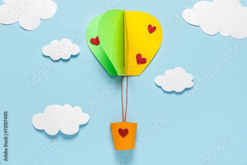 Paper hot air balloon with clouds on blue background. Valentine's Day celebration