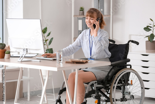 Young businesswoman in wheelchair talking by mobile phone at office