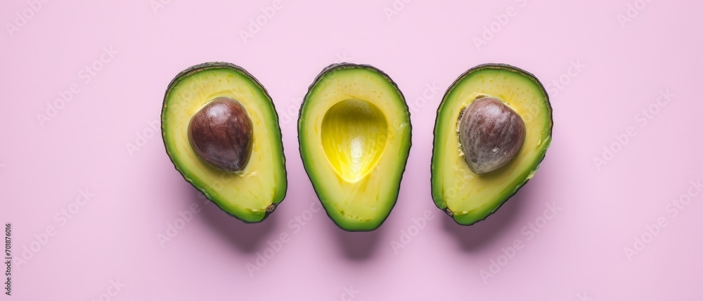 Avocado halves with pits on a pink backdrop, showcasing fresh and creamy texture. Avocado halves with pits on a pink backdrop, showcasing fresh and creamy texture.