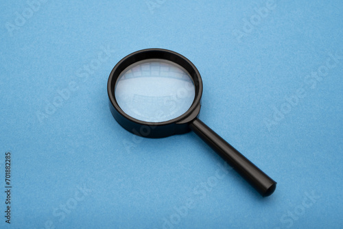 a magnifying glass on blue paper, essence of a searching engine concept quest for information and insights through a visual metaphor.