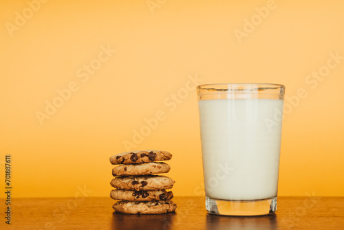 Delicious Breakfast: Cookies and Milk on a Wooden Table with an Orange Background.