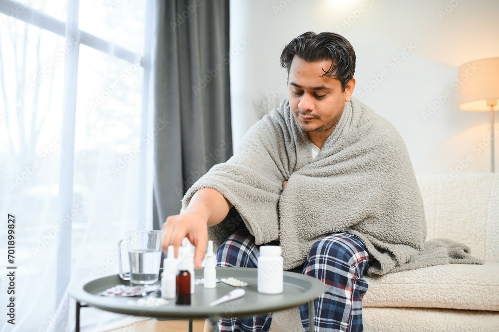 Sick young hindu man feeling bad in the morning, sitting on bed Sick young hindu man feeling bad in the morning, sitting on bed