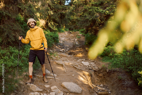photo of a man in a yellow light jacket and trekking poles traveling in the Carpathian Forest Mountains
