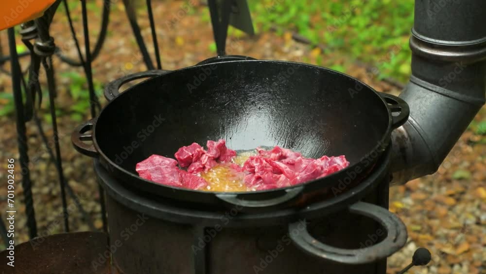 Cooking outdoors with cast iron pan. Frying meat. 4k video footage UHD 3840x2160 Cooking outdoors with cast iron pan. Frying meat. 4k video footage UHD 3840x2160