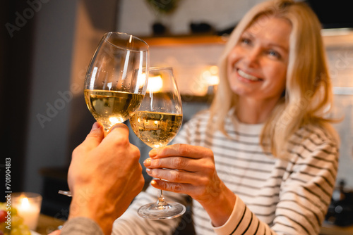 Focused photo of clinking glasses of wine with happy couple on the background during romantic date