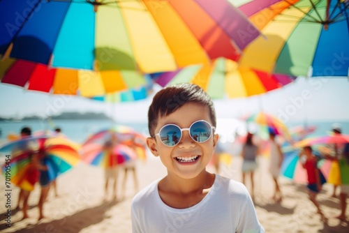 happy asian child boy on the beach in summer against the background of the sea or ocean and colorful umbrella