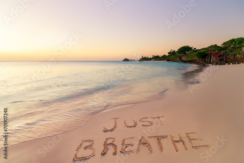 Handwritten Just breathe on sandy beach at sunset