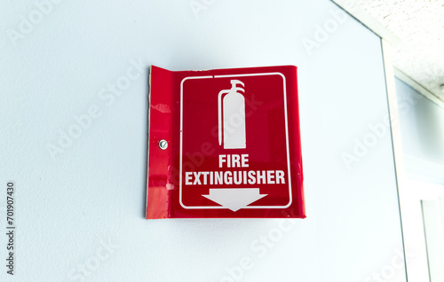 Red and white fire extinguisher sign on wall indicating emergency safety equipment presence
