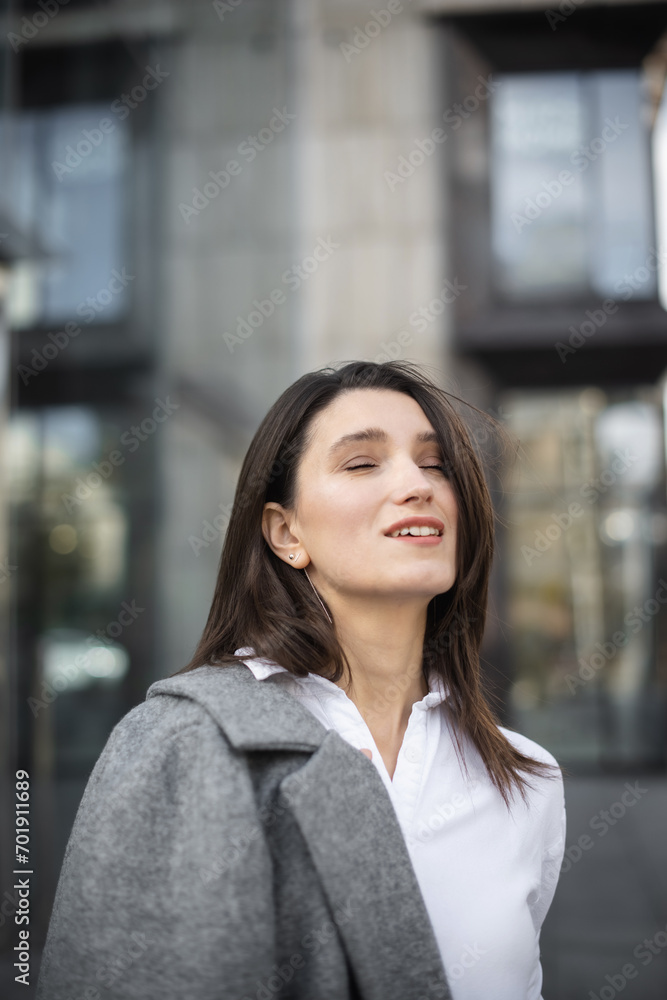 Businesswoman looking out while standing near modern office building. young female in formal wear standing outdoors
