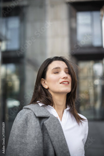 Businesswoman looking out while standing near modern office building. young female in formal wear standing outdoors
