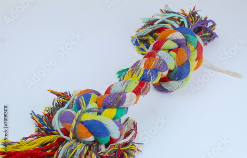 A close up photo of a colorful double knotted dog toy on a white surface. 