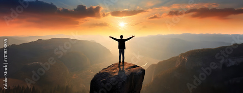 Person Embracing the Sunrise on a Mountain Summit. Silhouette of a person with arms raised embracing the sunrise at the top of a mountain summit