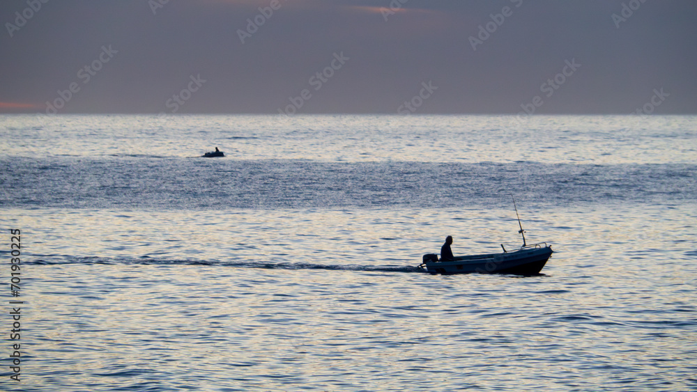 Pescador en su barco al amanecer en la costa de Granada, España Pescador en su barco al amanecer en la costa de Granada, España