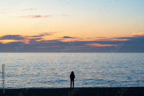 Silueta de mujer joven al amanecer el la orilla de la playa de Granada, España photo