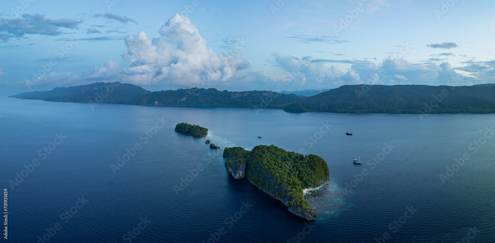 Dawn illuminates scenic limestone islands fringed by beautiful coral reefs in Raja Ampat, Indonesia. This region is known for its exquisite coral reefs and overall high marine biodiversity.