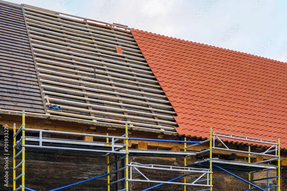 Installation of new clay tiles on new wooden battens on the roof of a historic house Installation of new clay tiles on new wooden battens on the roof of a historic house
