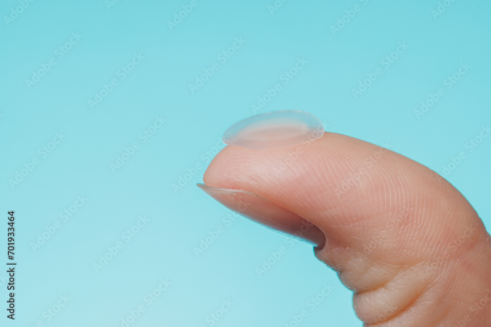 Close-up round acne patch on finger on blue background. Acne patches for treatment of pimple and rosacea close-up. Facial rejuvenation cleansing cosmetology Close-up round acne patch on finger on blue background. Acne patches for treatment of pimple and rosacea close-up. Facial rejuvenation cleansing cosmetology