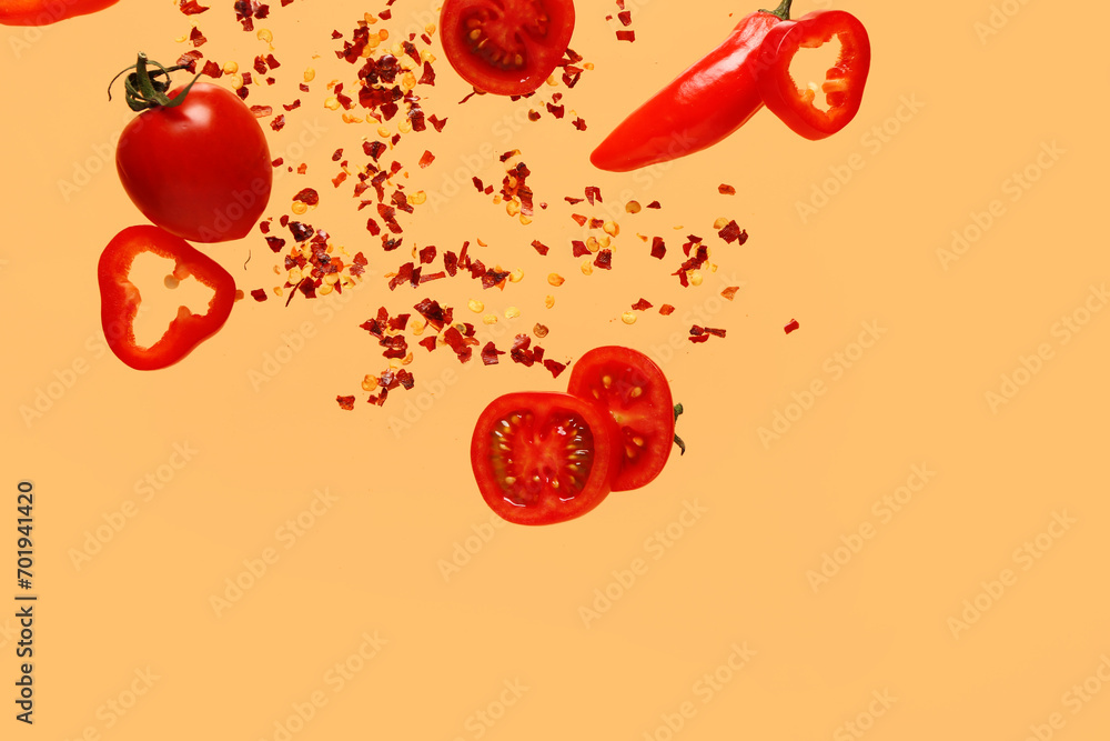 Fototapeta premium Flying vegetables and chili flakes on color background
