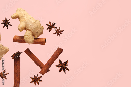 Flying cinnamon sticks, anise stars and ginger root on pink background