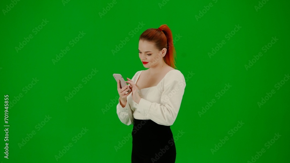 Portrait of attractive office girl on chroma key green screen. Woman in skirt and blouse holding smartphone and texting, happy face expression. Portrait of attractive office girl on chroma key green screen. Woman in skirt and blouse holding smartphone and texting, happy face expression.