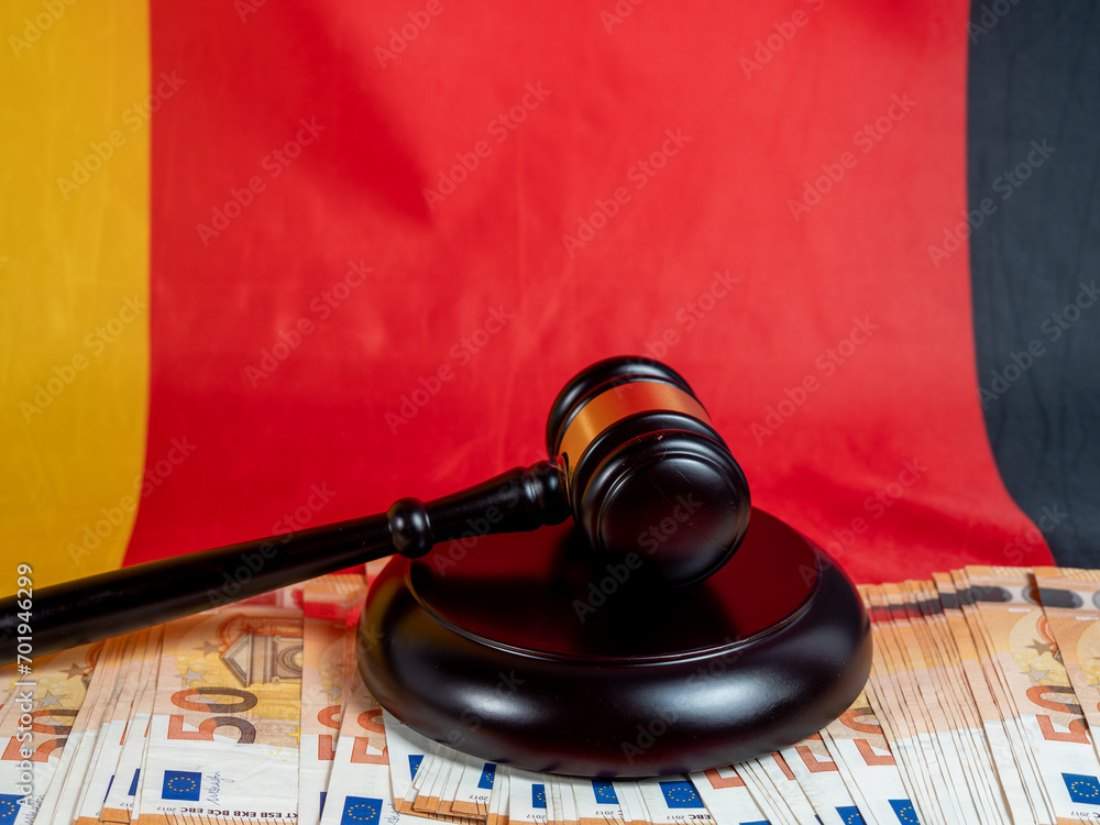 The judge's gavel lies on 50 euro bills against the background of the German flag. Law and justice concept.