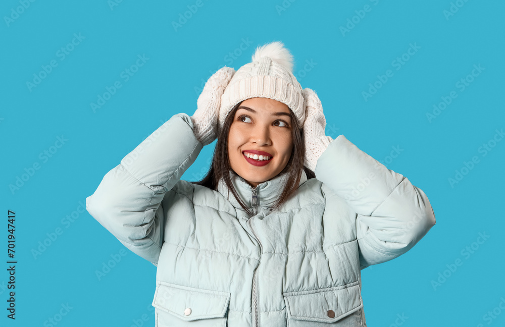 Young Asian woman in winter clothes on blue background Young Asian woman in winter clothes on blue background