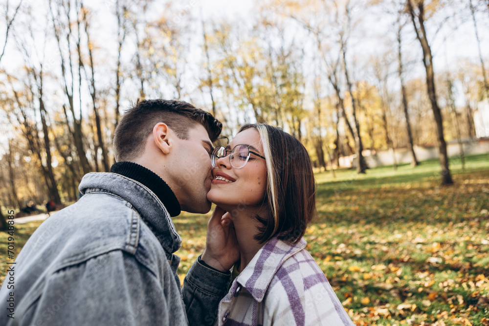 Heterosexual caucasian young loving couple walking outside in the city park in sunny weather, hugging smiling kissing laughing spending time together. Autumn, fall season, orange yellow red leaves
Heterosexual caucasian young loving couple walking outside in the city park in sunny weather, hugging smiling kissing laughing spending time together. Autumn, fall season, orange yellow red leaves