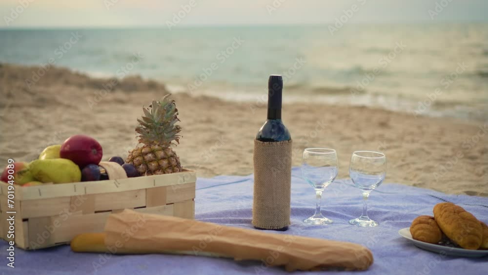 Picnic background with straw bag and wine bottle, fruits, baguettes and croissants on ocean beach. Food and drink for picnic at sea shore Picnic background with straw bag and wine bottle, fruits, baguettes and croissants on ocean beach. Food and drink for picnic at sea shore