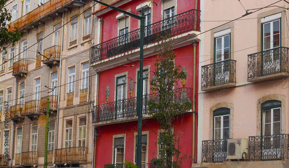 Exterior facades of historical houses with apartments in Lisbon, Portugal. Urban vintage background. Alfama district. The building is tiled with carved balconies.