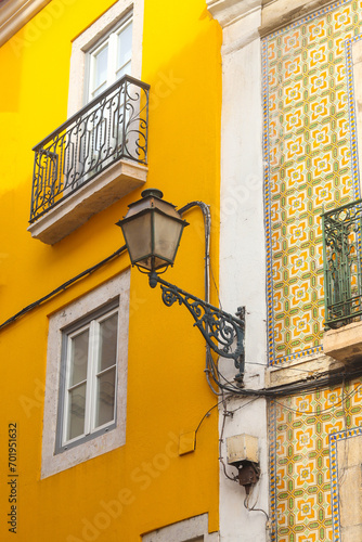 Exterior facade of yellow historical house with apartments in Lisbon, Portugal. Urban vintage background. Alfama district. The building is tiled with carved balconies.