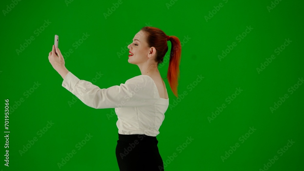 Portrait of attractive office girl on chroma key green screen. Woman in skirt walking holding gift bags taking selfie on smartphone. Side view. Portrait of attractive office girl on chroma key green screen. Woman in skirt walking holding gift bags taking selfie on smartphone. Side view.