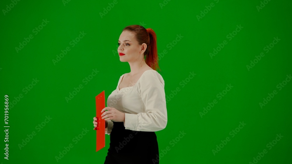 Portrait of attractive office girl on chroma key green screen. Woman in skirt and blouse walking holding red folder. Half turn. Portrait of attractive office girl on chroma key green screen. Woman in skirt and blouse walking holding red folder. Half turn.
