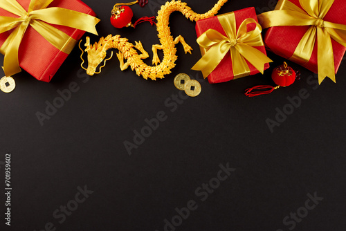 Traditional tokens of goodwill for Chinese New Year. Top view photo of gold dragon, elegant gift boxes, lucky coins, lanterns on black background with promo space