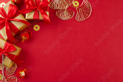 Symbolic gifts for Chinese New Year celebrations. Top view shot of gift boxes, ginkgo biloba, lucky coins, lanterns on red background with ad panel
