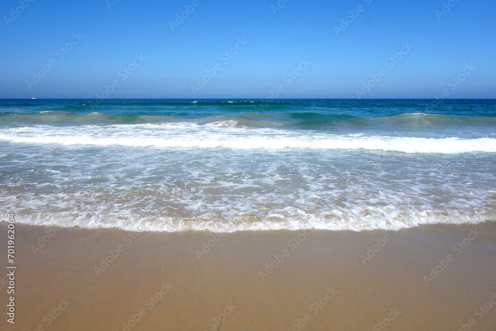 Gentle ocean breeze pushes rolling waves slowly toward wet sand of Pacific beach in San Diego, California