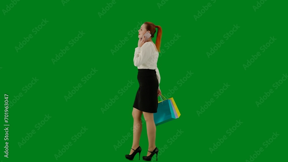 Portrait of attractive office girl on chroma key green screen. Woman in skirt and blouse walking talking on smartphone, positive face expression. Side view. Portrait of attractive office girl on chroma key green screen. Woman in skirt and blouse walking talking on smartphone, positive face expression. Side view.