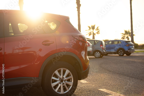Parked cars on the street with a red car in the foreground