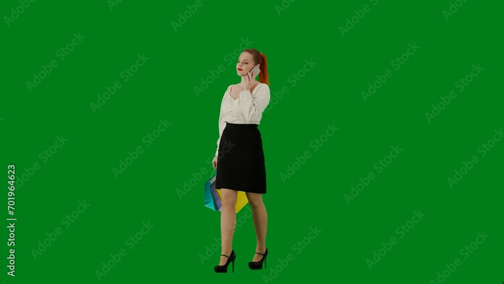 Portrait of attractive office girl on chroma key green screen. Woman in skirt and blouse walking talking on smartphone, positive face expression. Half turn. Portrait of attractive office girl on chroma key green screen. Woman in skirt and blouse walking talking on smartphone, positive face expression. Half turn.