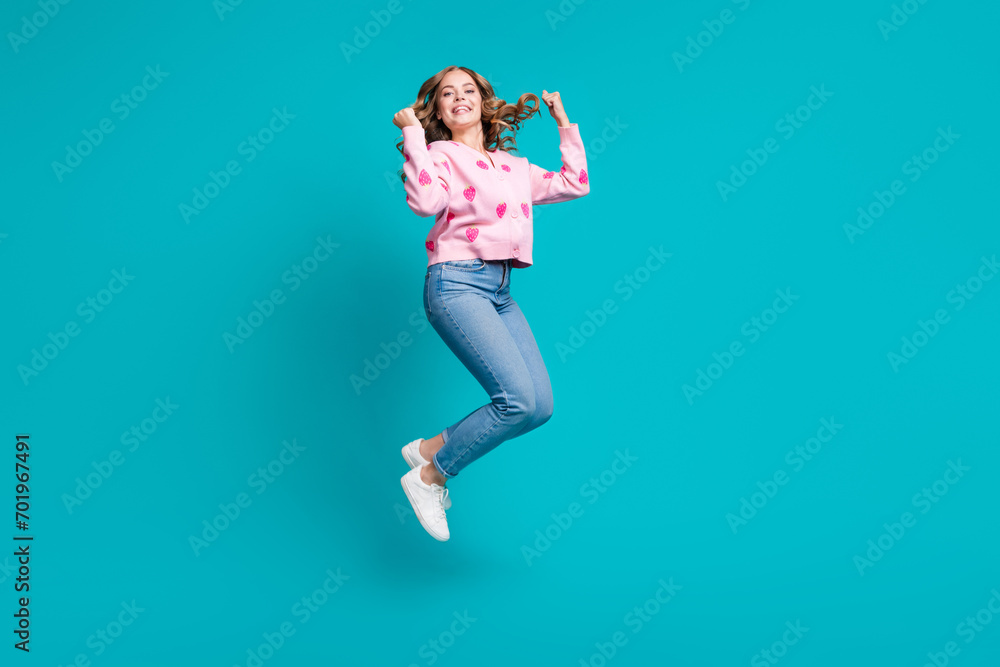 Full body length photo of energetic young woman pink cardigan jumping raised fists up triumph champion isolated on blue color background