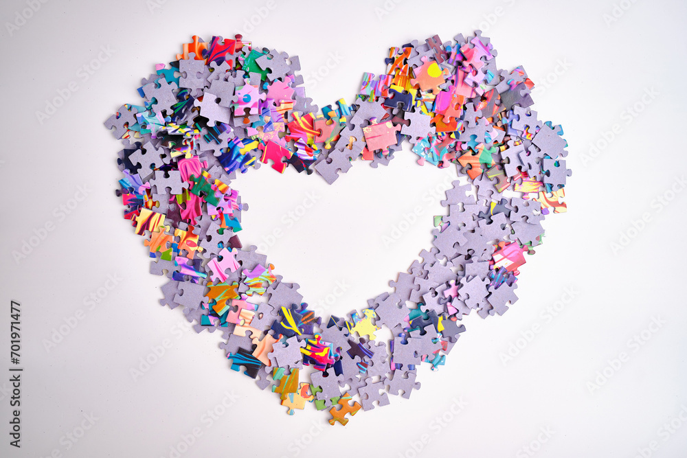 Many puzzle pieces in the shape of a heart. Background image of scattered colorful puzzle pieces Many puzzle pieces in the shape of a heart. Background image of scattered colorful puzzle pieces