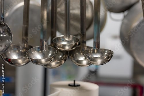Stainless steel cooking utensils hanging in a commercial industrial kitchen. 