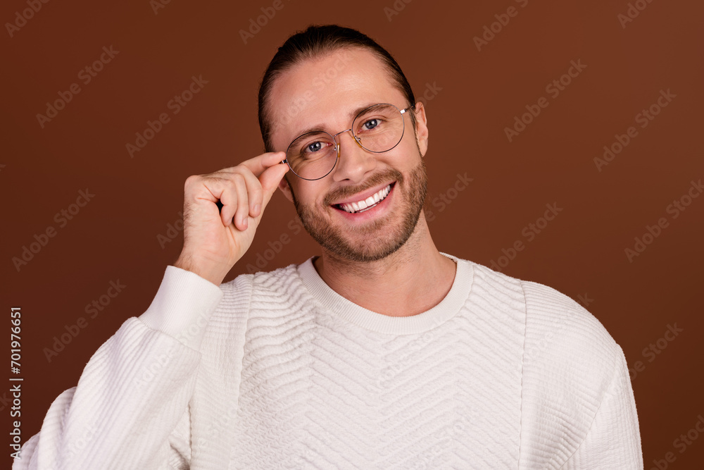 Photo of confident funky man wear white sweater arm hand spectacles smiling isolated brown color background Photo of confident funky man wear white sweater arm hand spectacles smiling isolated brown color background