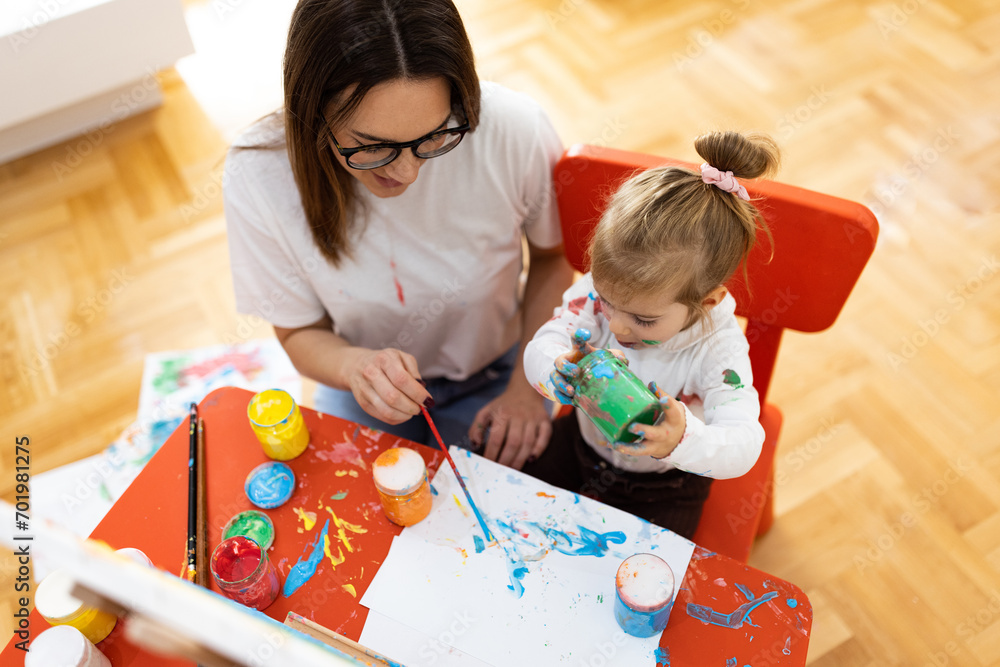 Fototapeta premium The little girl and her mother enjoy painting, they are all dirty but happy