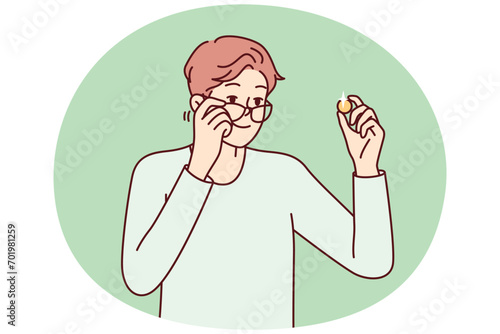 Positive man examines gold coin or piece of jewelry and lowers glasses from eyes to view rare exhibit. Guy is fond of numismatics and collecting coins from precious metals. Flat vector design