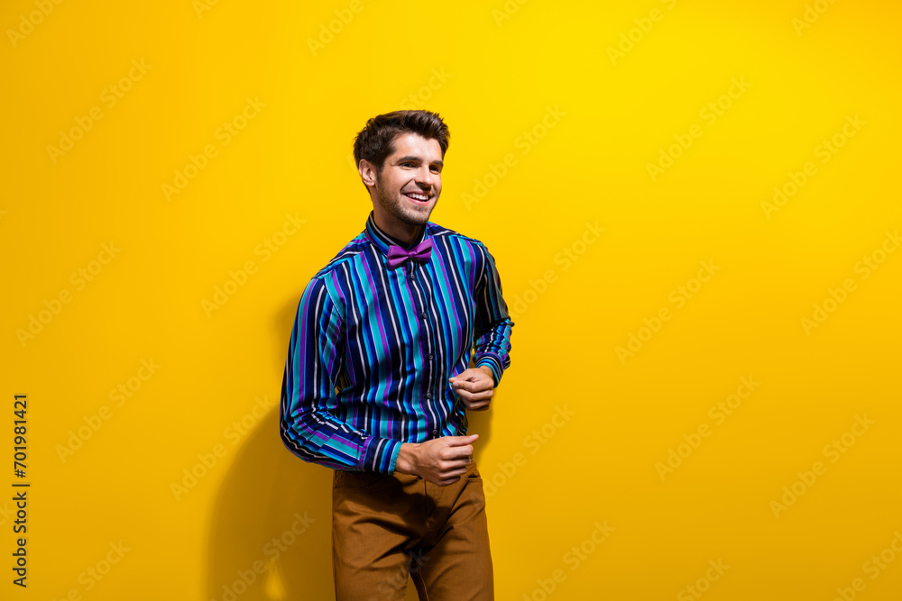 Photo of good mood man with bristle dressed striped shirt bow tie having fun at disco party isolated on vivid yellow color background Photo of good mood man with bristle dressed striped shirt bow tie having fun at disco party isolated on vivid yellow color background