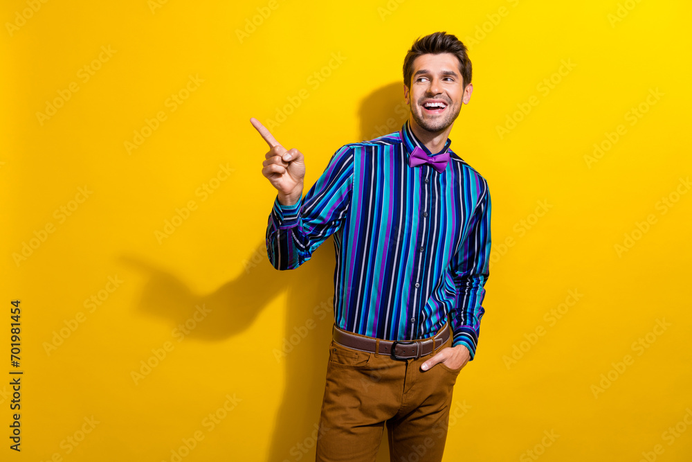 Photo of good mood gentleman dressed striped shirt tie bow directing look at promo empty space isolated on vivid yellow color background Photo of good mood gentleman dressed striped shirt tie bow directing look at promo empty space isolated on vivid yellow color background