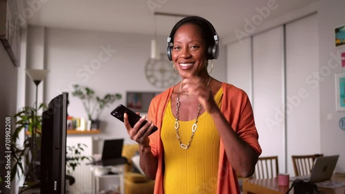 Woman listening to music with headphones connected to her smartphone in the living room at home