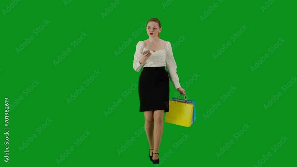 Portrait of attractive office girl on chroma key green screen. Woman in skirt walking holding gift bags and texting on smartphone, smiling face. Portrait of attractive office girl on chroma key green screen. Woman in skirt walking holding gift bags and texting on smartphone, smiling face.